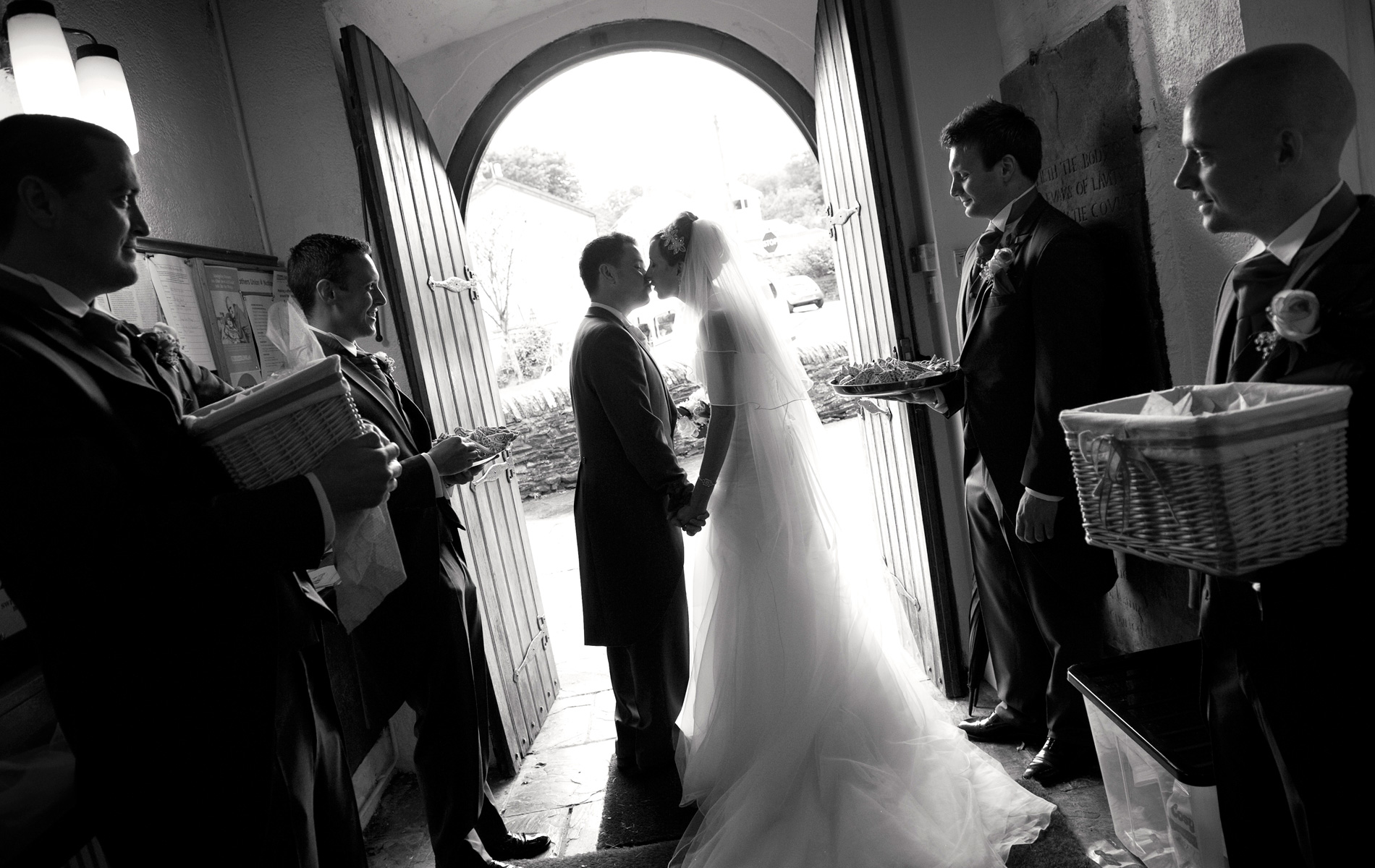 Pontypridd-wedding-photographer-Bride-Groom-kissing-doorway-St-Illtud's-Church-Church-Village.