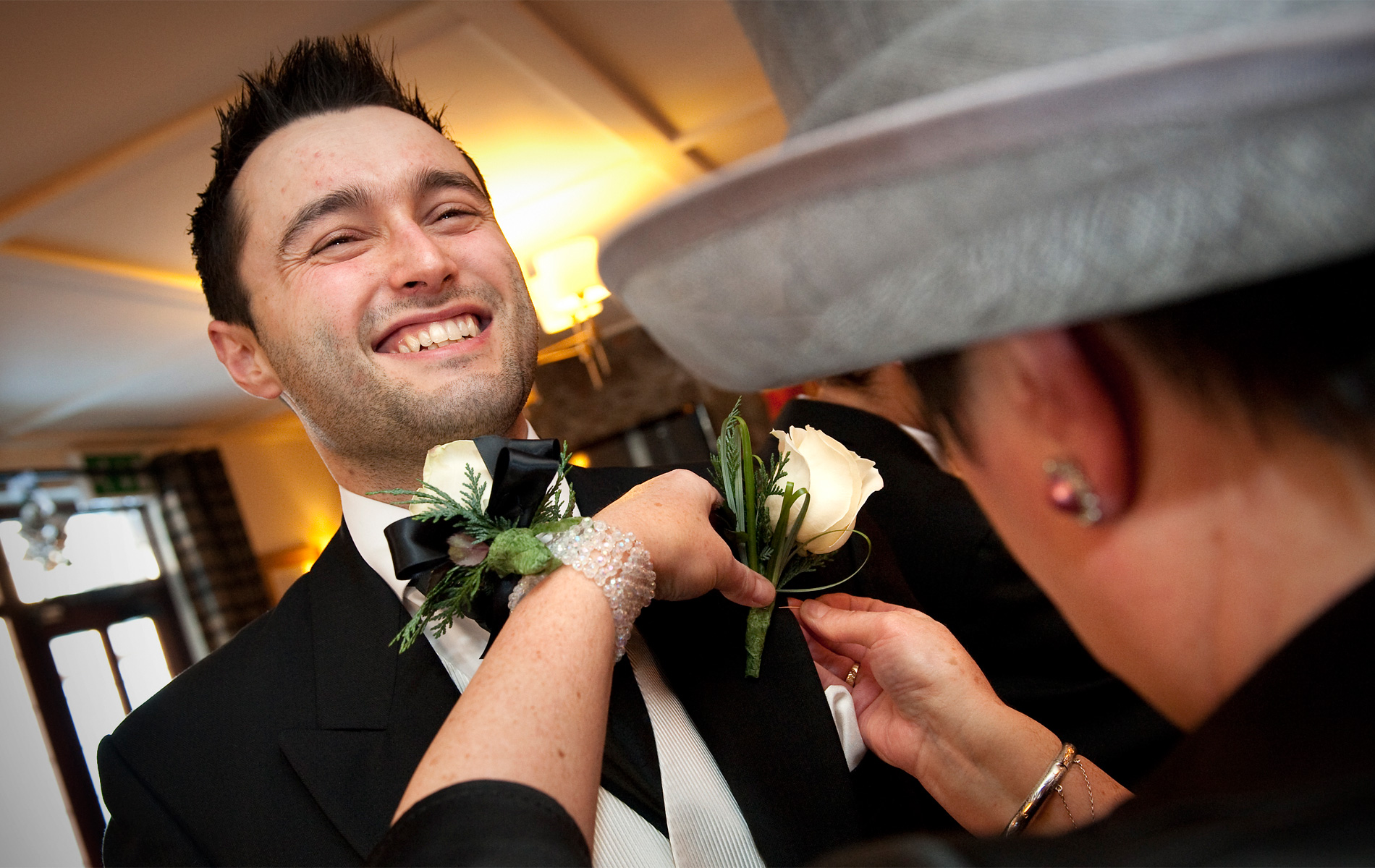 Bridgend-wedding-photography-grooms-mother-attaching-groom's-buttonhole-Pheasant-Inn-Pen-y-Fai